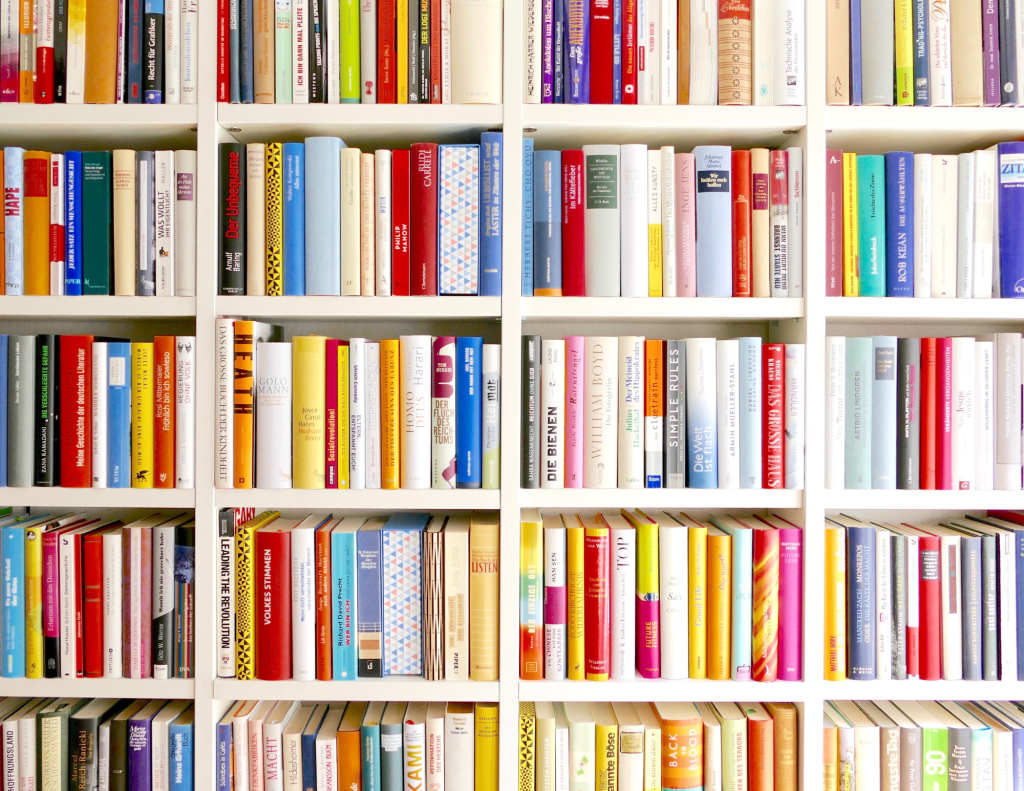 colorful book spines on a white shelf.